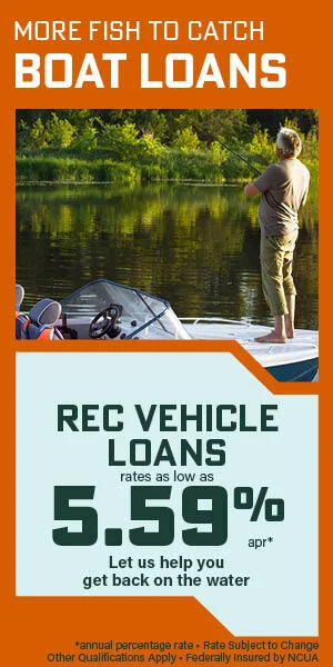 Man fishing in lake surrounded by trees from boat 