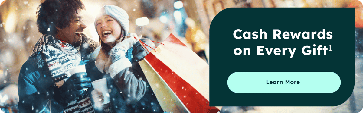 Happy couple dress in scarves, winter hats, gloves, and coat with hot chocolate in each of their hands and shopping bags in the other.